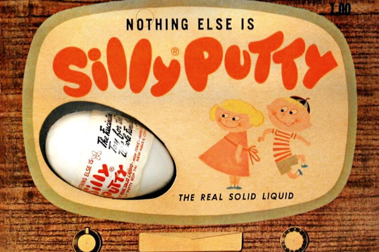 Silly Putty in its classic red plastic egg, opened to reveal the stretchy, bouncy putty inside — a timeless toy born from accidental innovation.